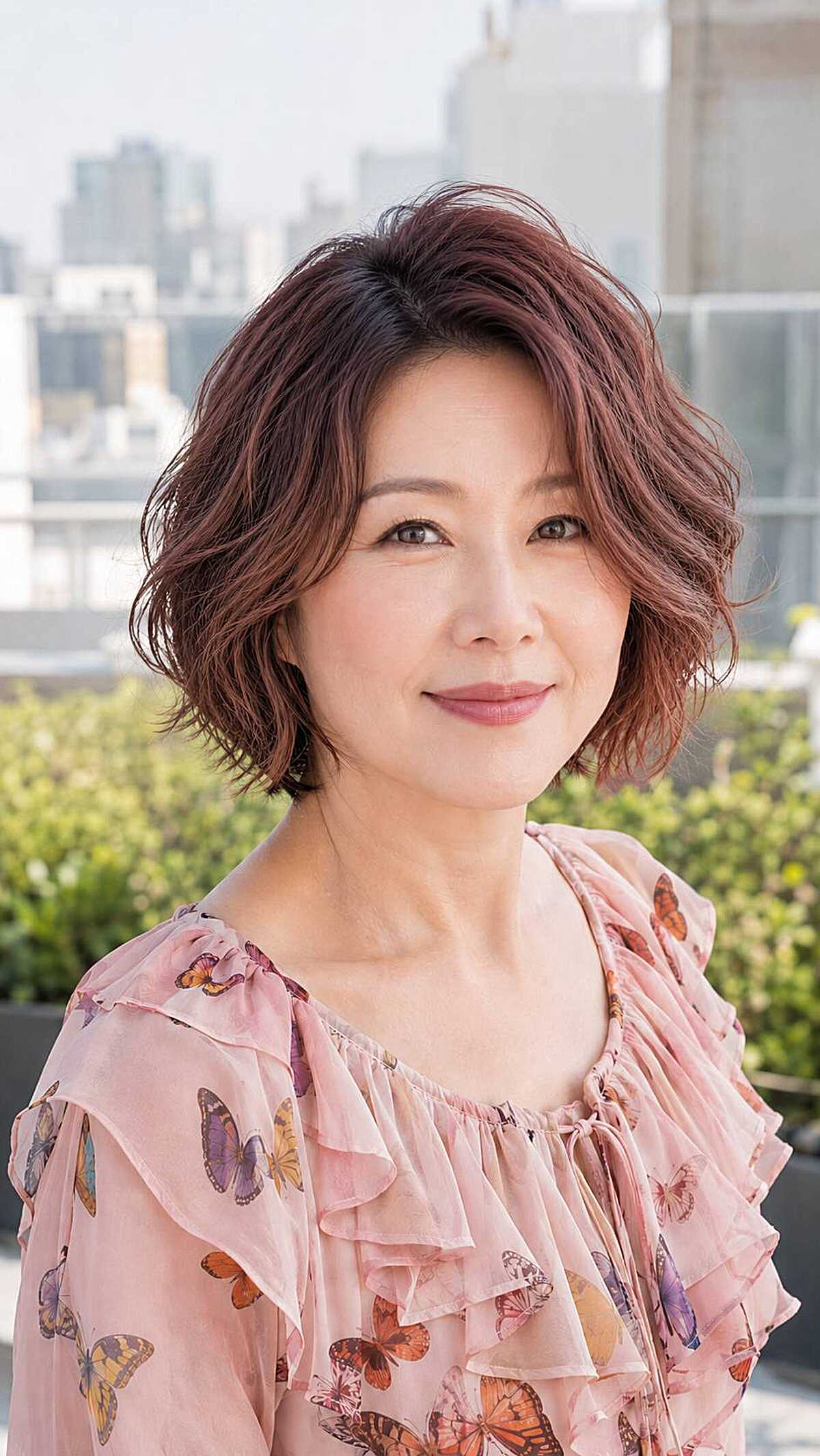 Tousled rosy auburn wavy textured bob on older woman