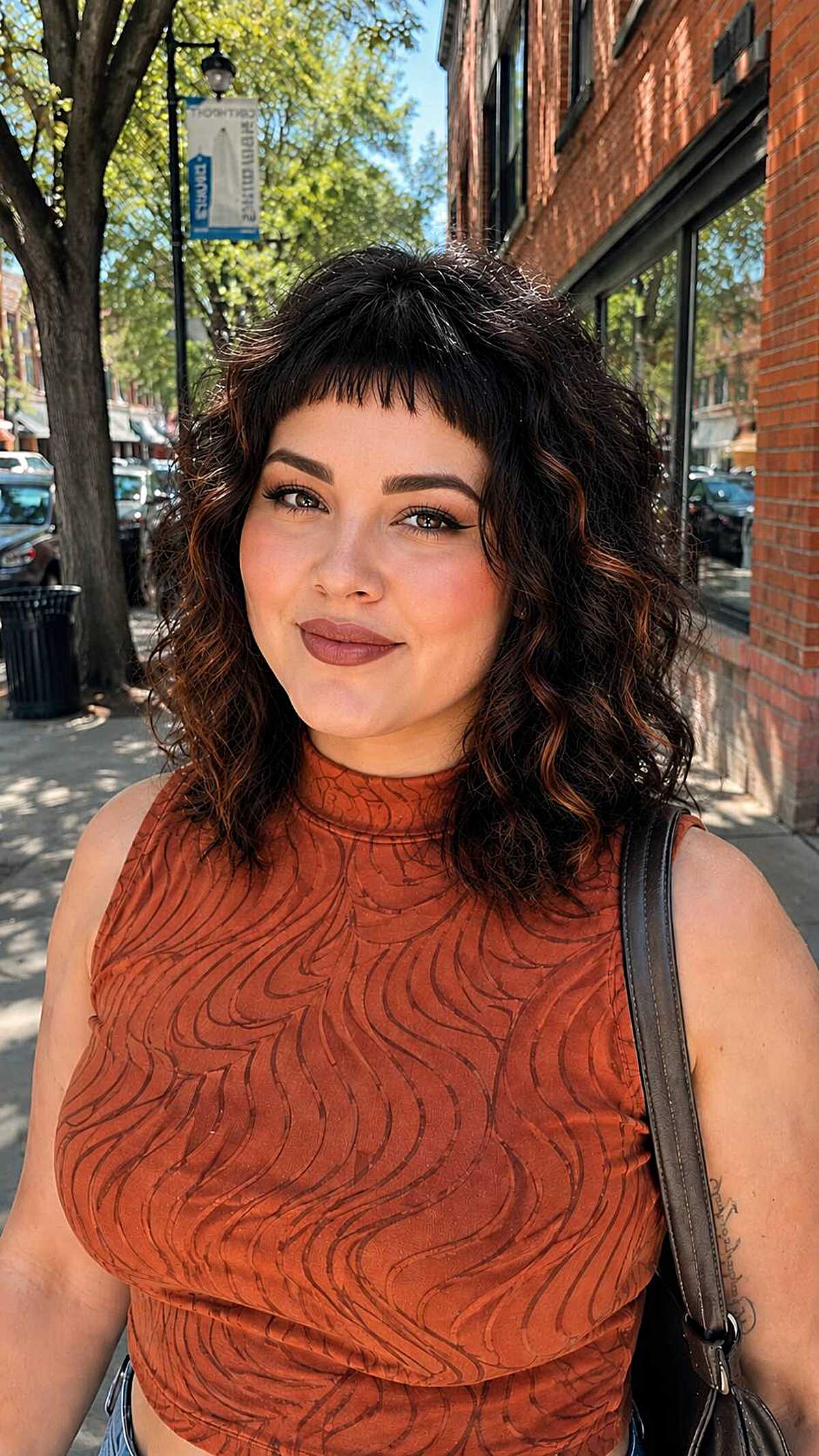 Curly dark shag haircut with choppy bangs and copper ends