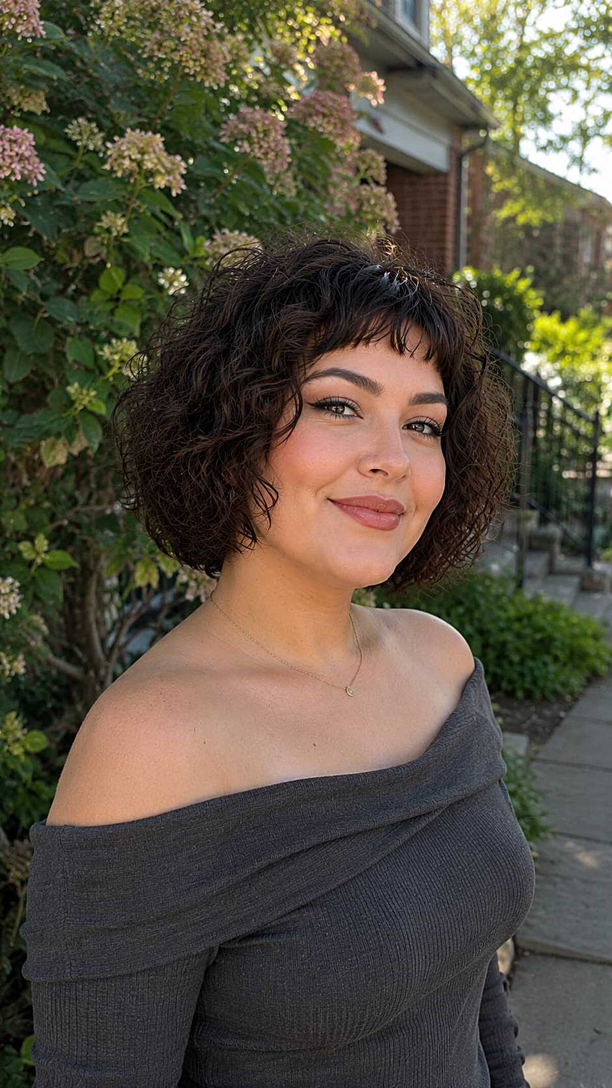 Short curly bob with soft baby bangs on round face