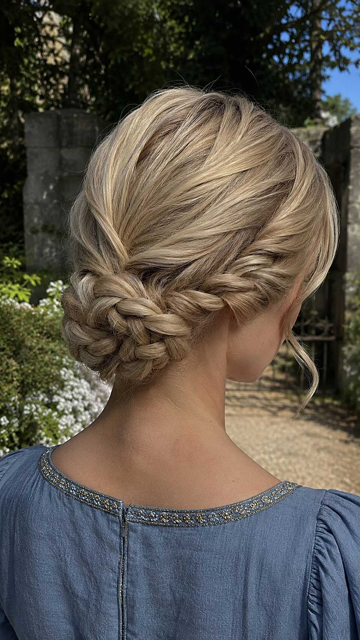 Blonde fishtail braid wrapped into a low bun updo