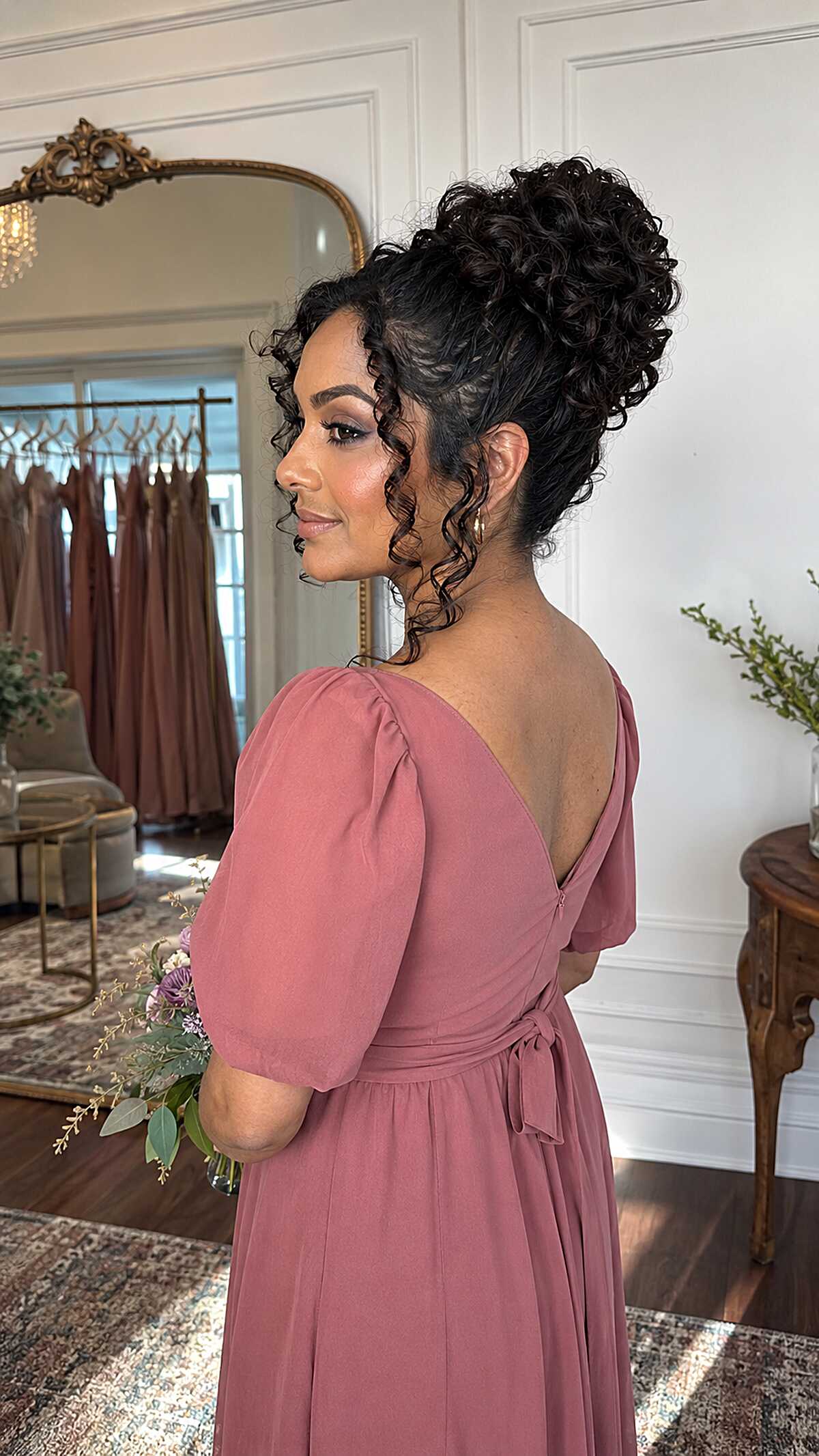 Curly High Bun with Intentional Face-Framing Tendrils