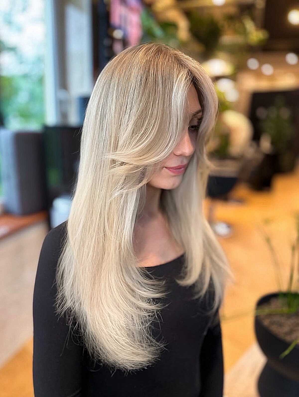 Long straight ashy blonde hair with feathered layer tips