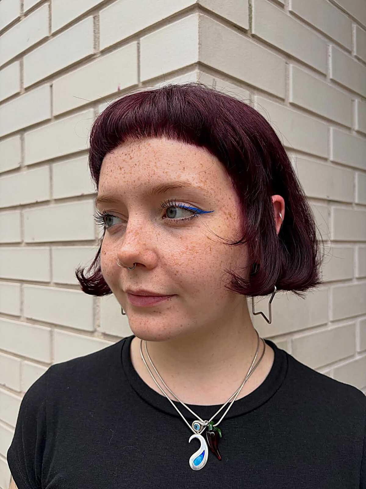 Short deep plum bob with baby bangs and curled ends