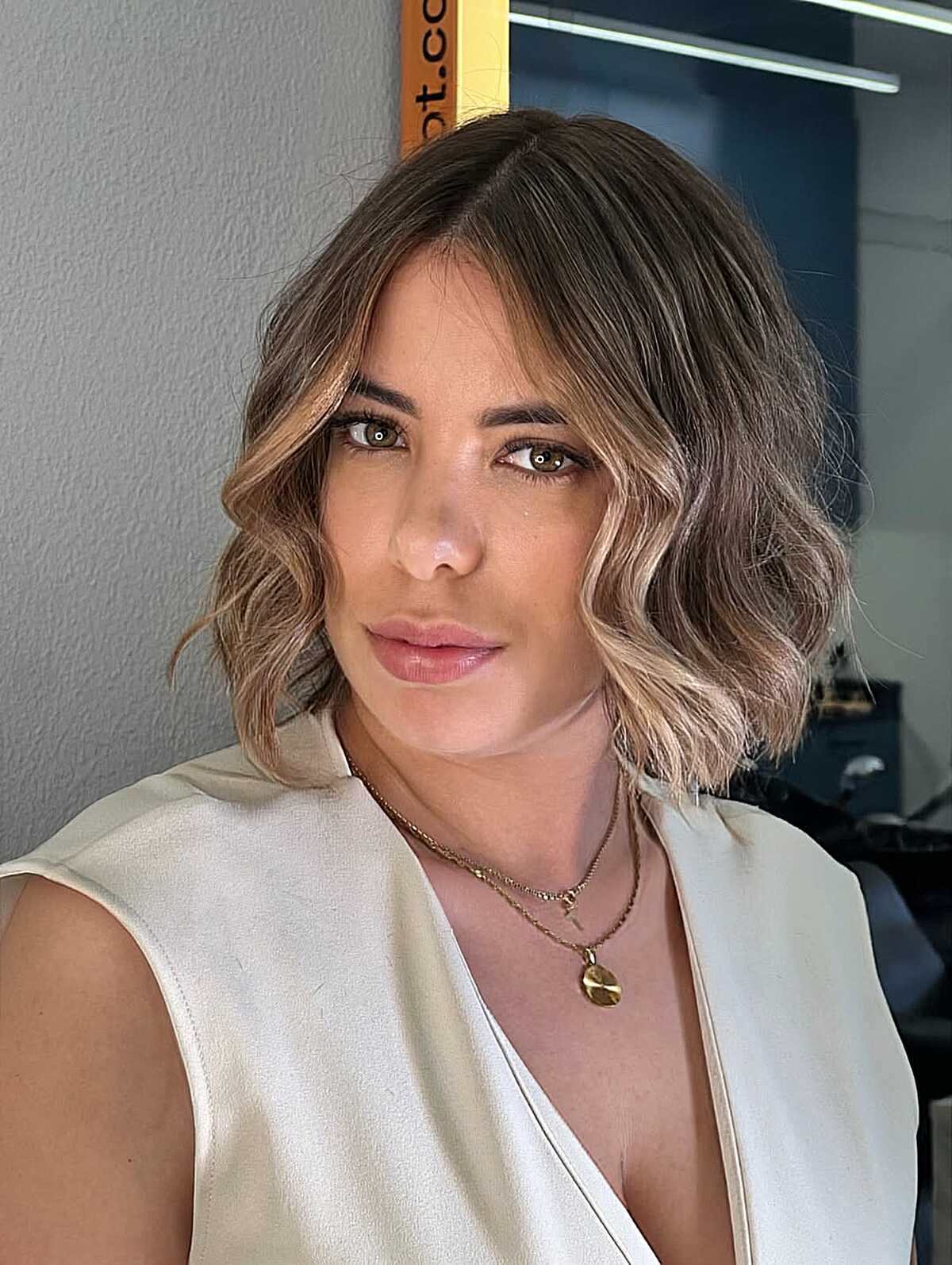 Wavy brunette lob with warm blonde balayage highlights