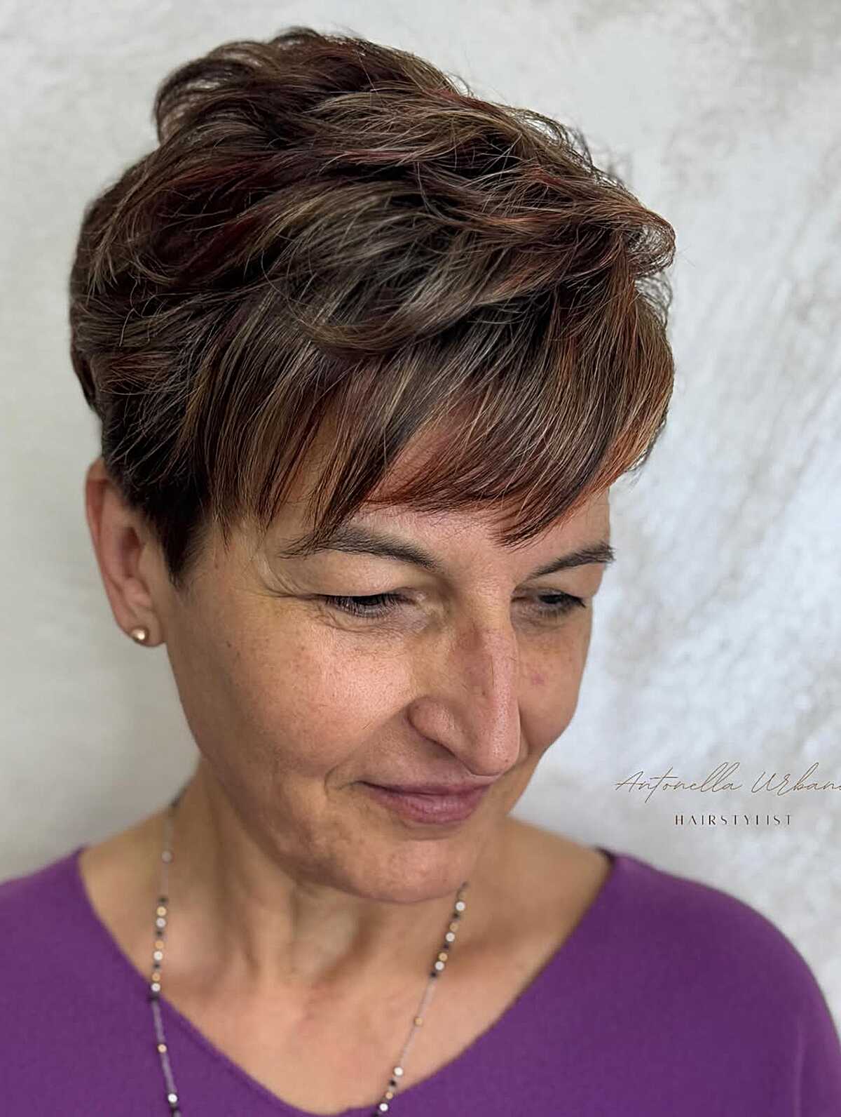 Auburn wavy pixie with copper highlights on mature woman