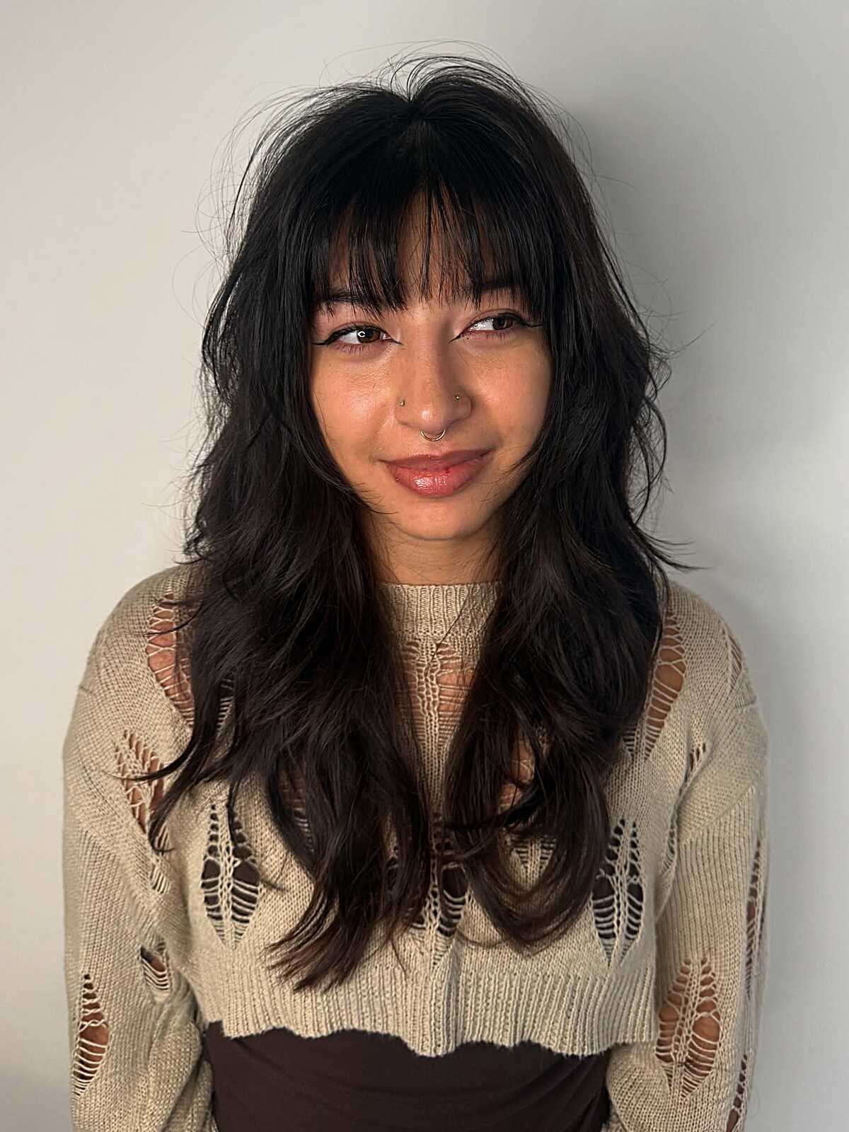 Long dark shag haircut with full bangs and texture