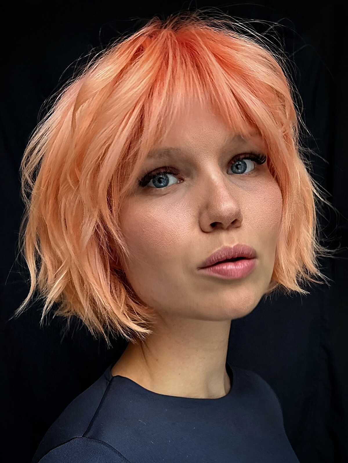 Peach-colored choppy bob shag with full bangs